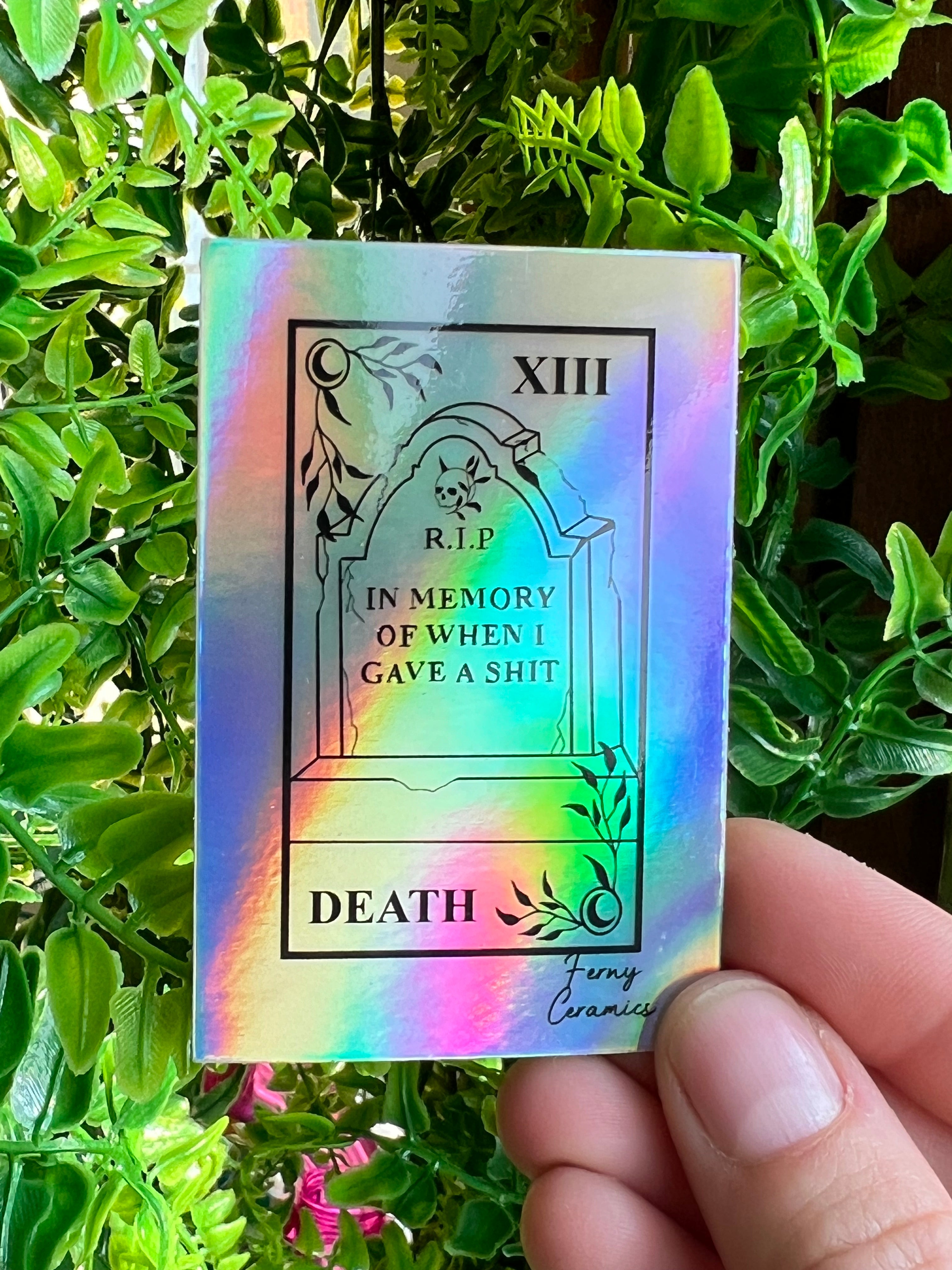 A person is holding a 2x3 Rectangular Holographic Sticker by Ferny Ceramics.