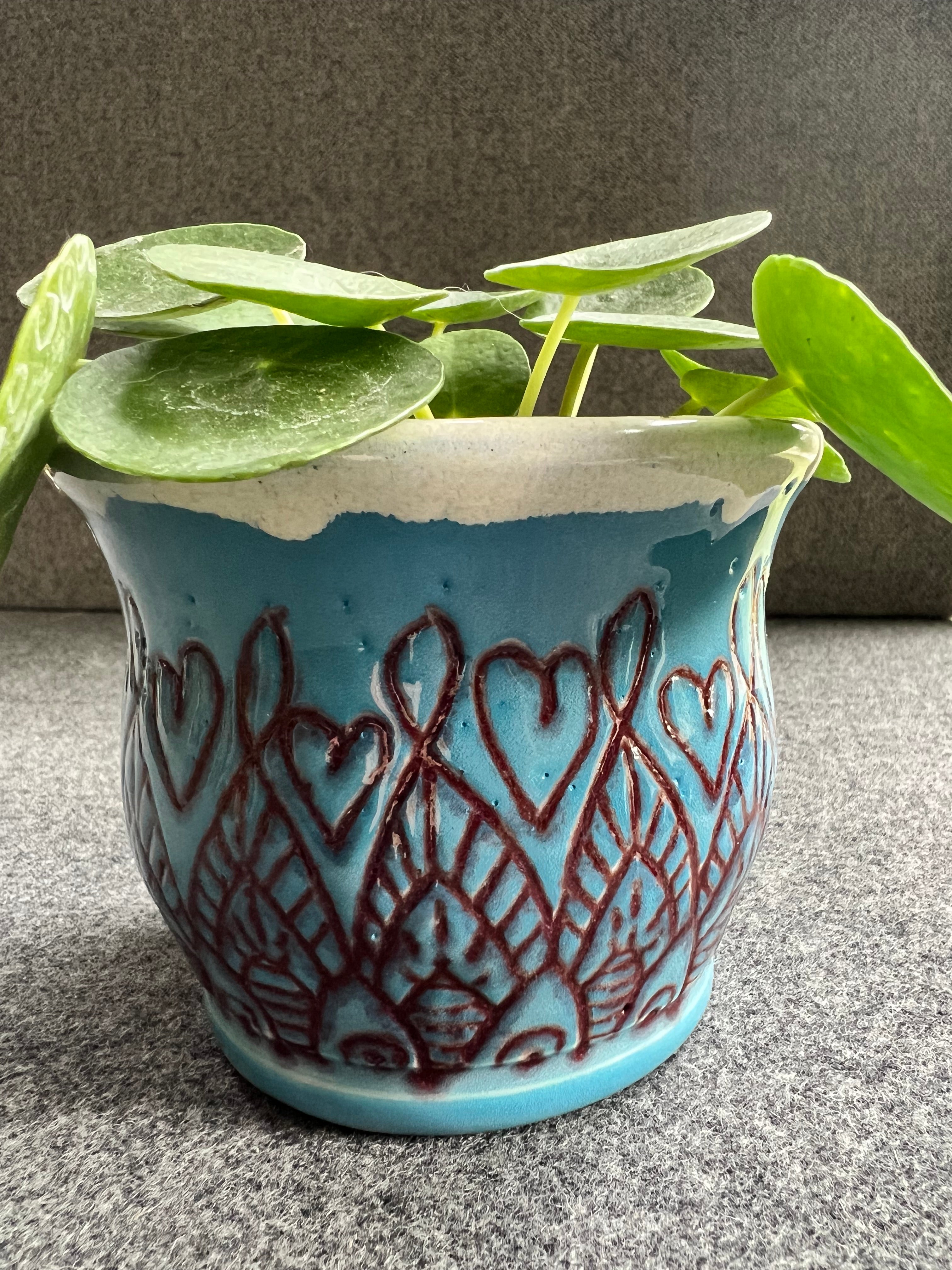 Beautifully crafted blue pot featuring hearts and a unique red design.