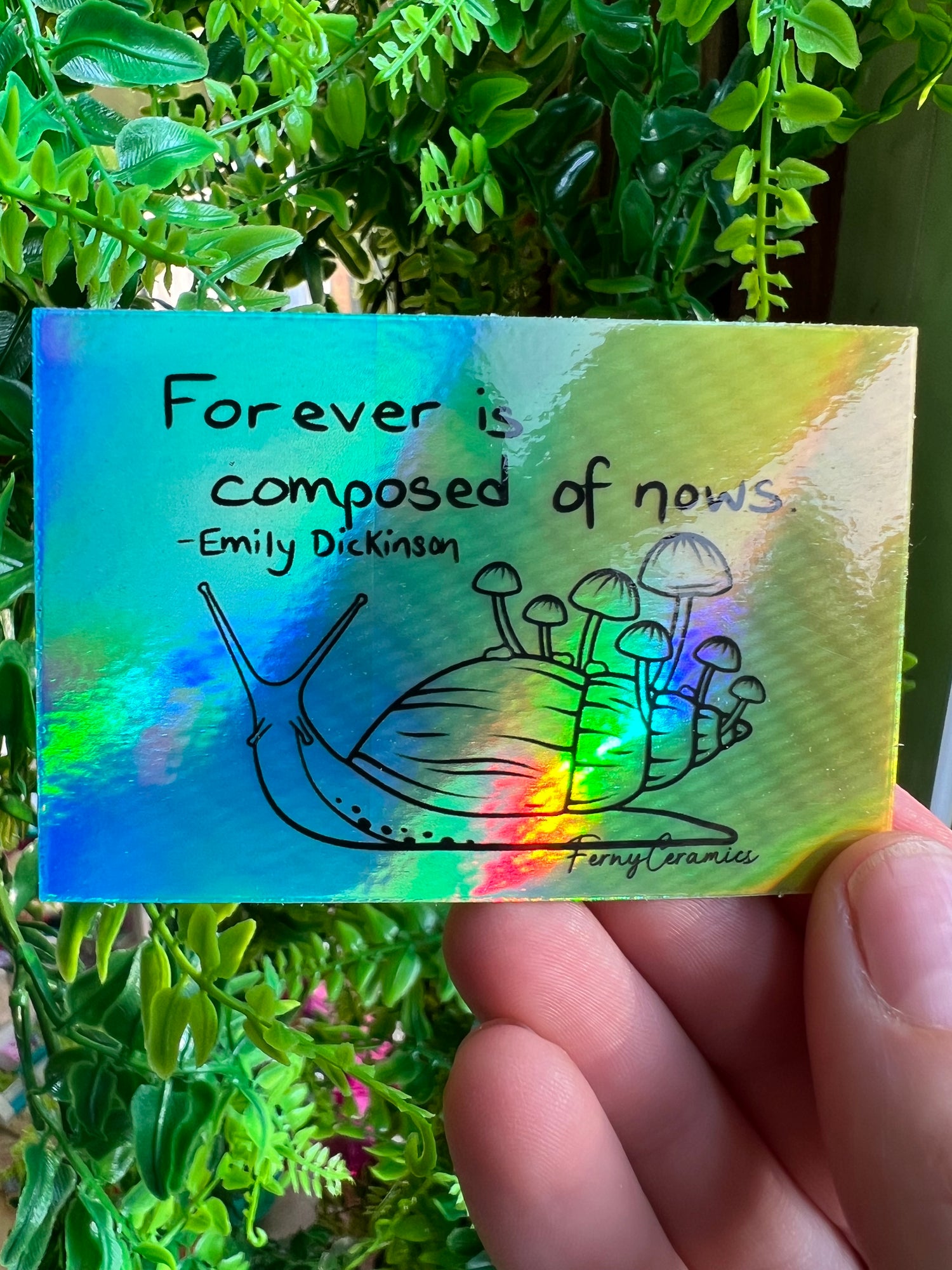 A person holding a Ferny Ceramics 3x2 Rectangular Holographic Stickers card that says forever is composed of news.